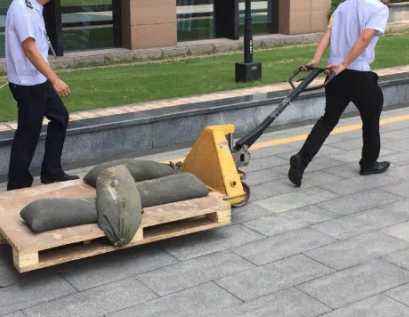 大工廠利用手動液壓搬運車搬運沙袋為防汛做準(zhǔn)備